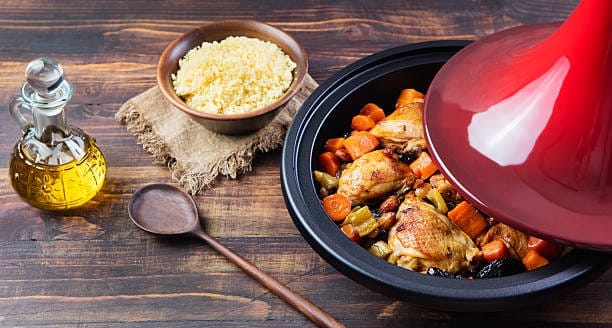 Moroccan chicken tagine served in a traditional Moroccan vessel called tagine with a side dish of rice and olive oil 