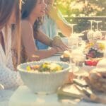 A lunch table with people enjoying their favorite dishes with some wine and champagne