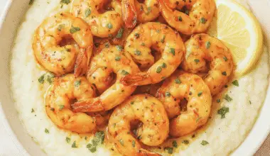 A bowl of creamy cauliflower grits topped with garlic butter shrimp, fresh parsley, and lemon — a healthy, low-carb twist on Southern shrimp and grits.