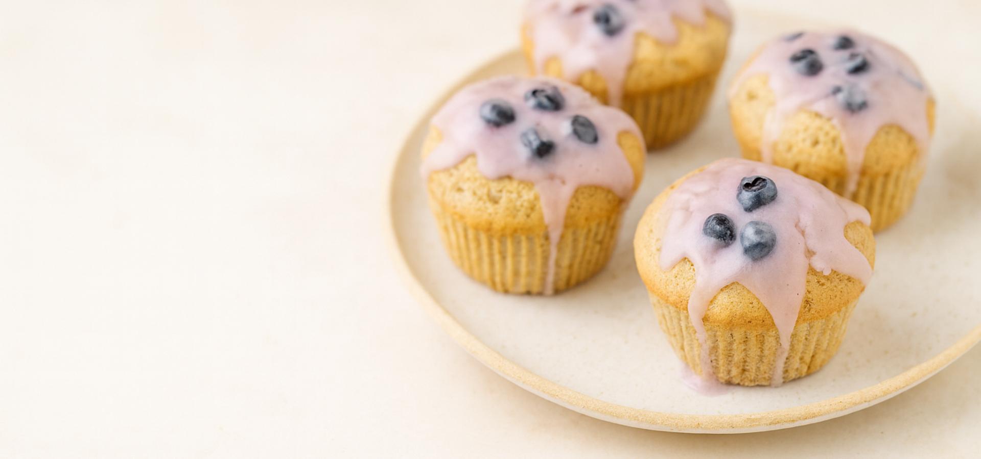 Lavender lemon poppy seeds topped with blueberries muffins with glaze on a cream platter – CaliYum healthy gluten-free baking